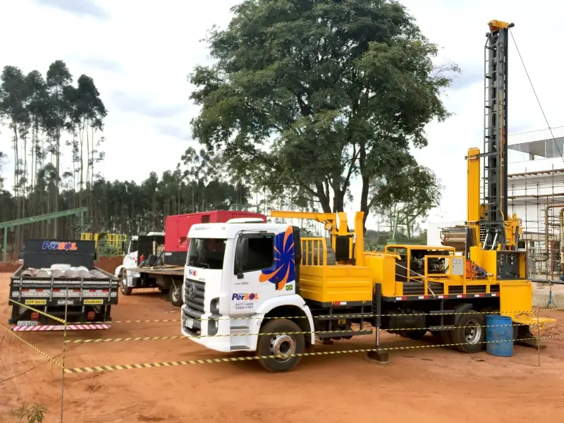 Sonda montada no canteiro isolado por fita zebrada, com a equipe trabalhando junto ao caminhão